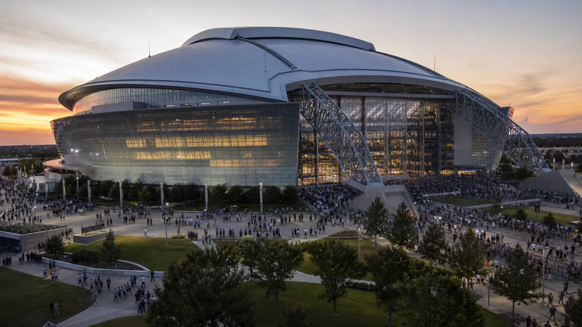 Huge silver retractable-roof football stadium in Arlington glowing at sunset