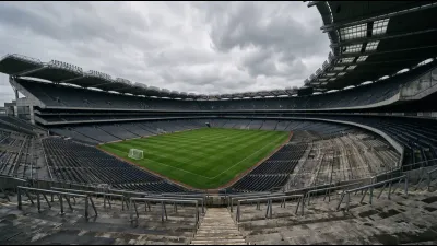 A large stadium bowl with a single open standing terrace at one end, seen from the upper tier under a soft grey Irish sky