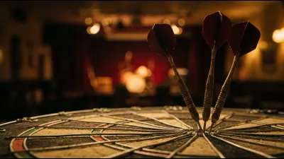 Three brass-barrelled darts with dark flights embedded in a worn plain sisal dartboard, lit from the side against a dim out-of-focus hall