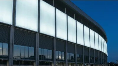 Blank illuminated white lettering panels mounted on a modern stadium facade at dusk, with no text on them